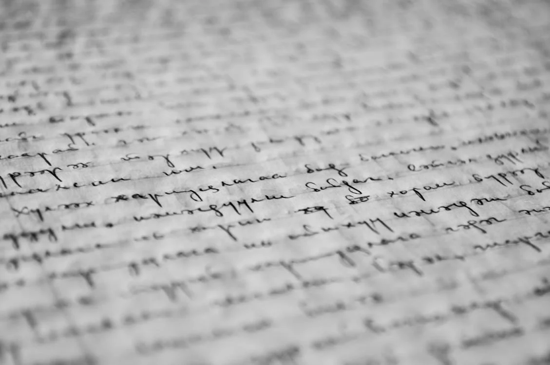 Close-up of handwritten text on paper, showing cursive writing in black ink. Close-up of handwritten text on paper, showing cursive writing in black ink.